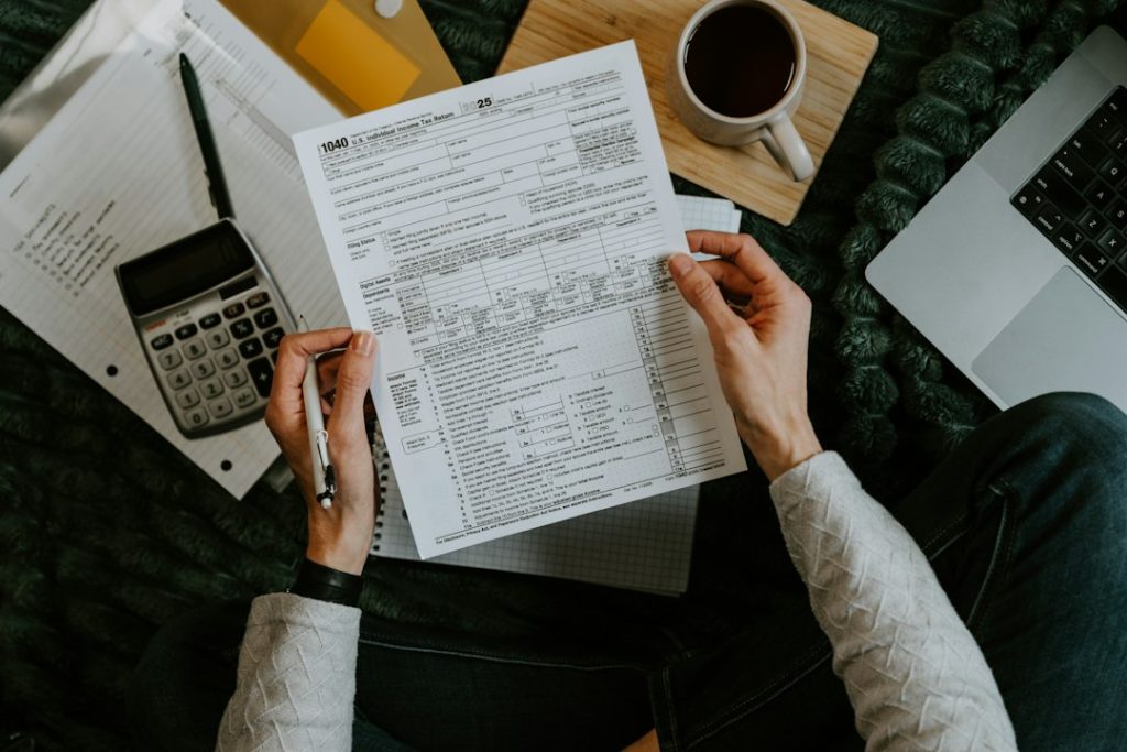 Hands processing invoices with a calculator and laptop, representing accounts payable automation